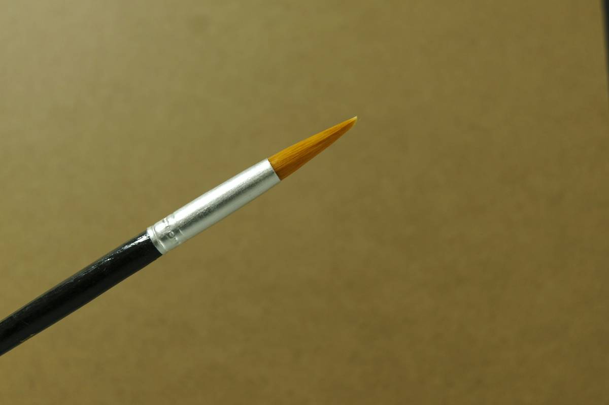 Fine-tip lip brush applying crimson lipstick along upper lip contour with surgical precision