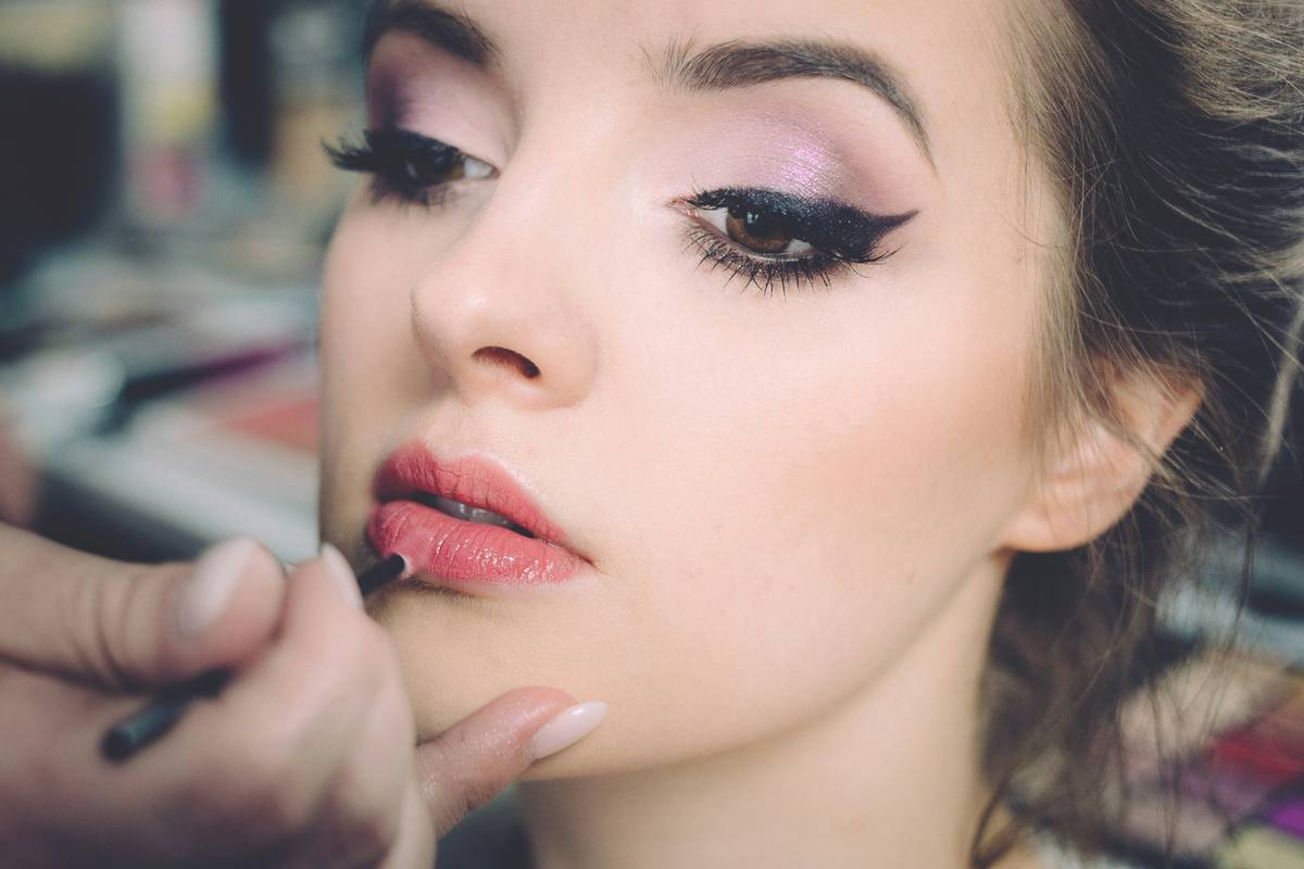 Close-up of a lip defining tool applying red lipstick along the cupid's bow with precision